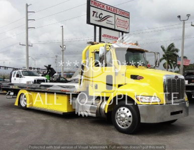 Yellow Peterbilt 337 rollback tow truck in dealership lot, front-right view, stock number J56560.
