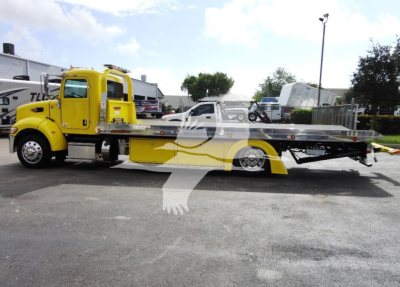 Peterbilt 337 rollback tow truck in yellow with flatbed, side view showing cab and truck bed.