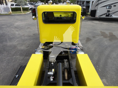 Yellow Peterbilt 337 rollback truck chassis with hydraulic rams and control levers visible, rear view showing bright yellow cab and frame, stock number J56560.