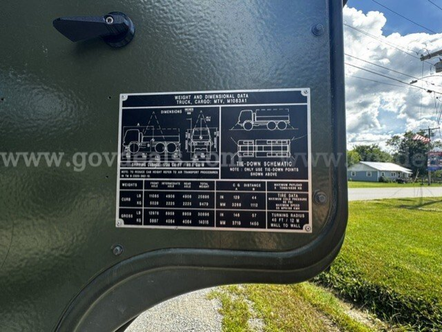 Truck data plate on exterior of green military truck showing weight and dimensional data, diagrams of vehicle and bed, and textual specifications.