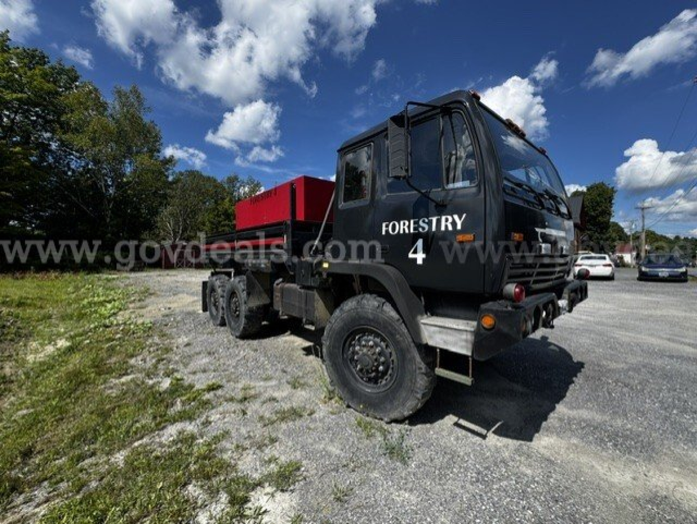 Truck cab with 'FORESTRY 4' marking, Stewart & Stevenson M1083A, rugged chassis, red equipment bed, front grille and large off-road tires visible.
