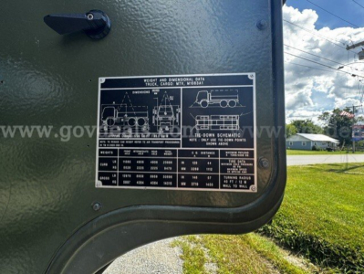 Truck data plate on exterior of green military truck showing weight and dimensional data, diagrams of vehicle and bed, and textual specifications.