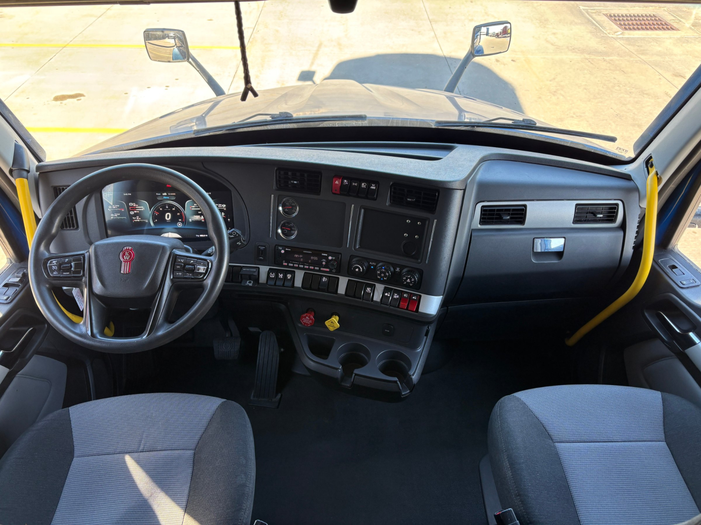 Kenworth T680 truck cab interior view showing steering wheel, dashboard, and control panel with gauges and switches.