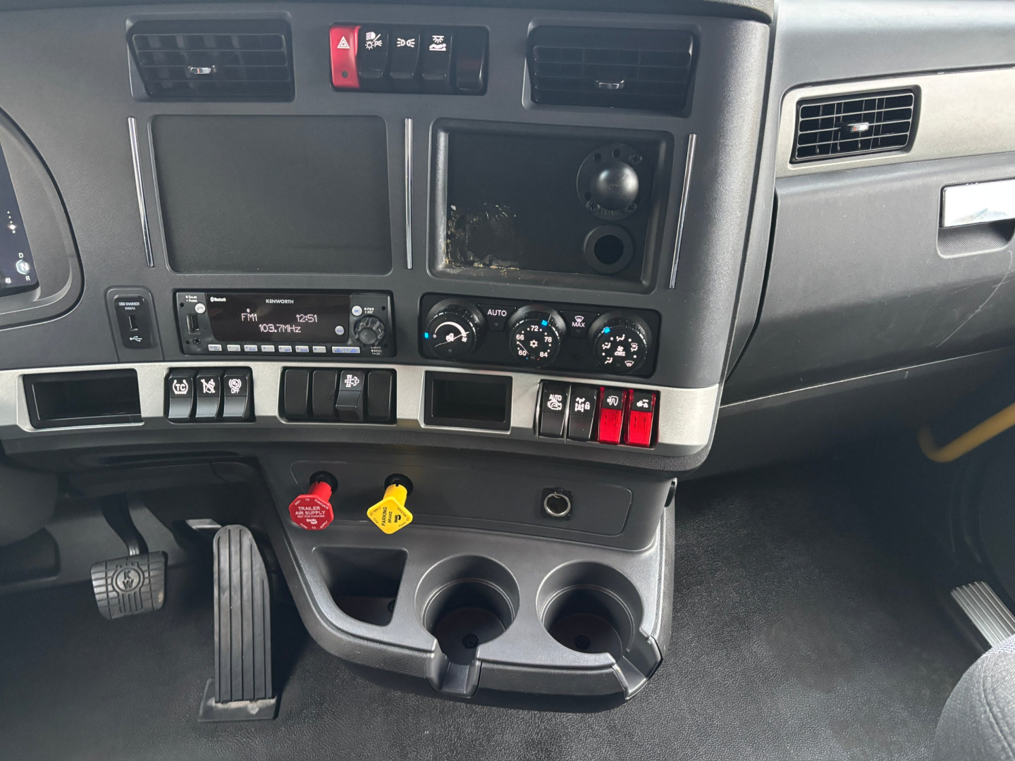 Kenworth T680 dash area showing center console with two cup holders, ignition area, controls, and empty screen slot.