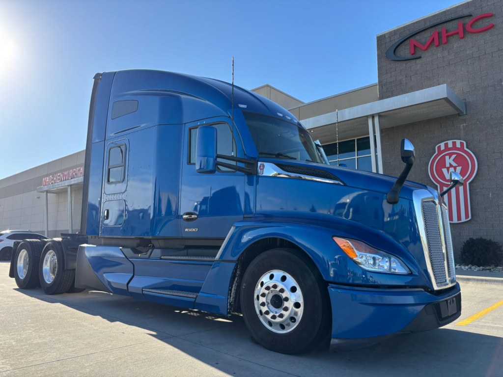 Kenworth T680 tractor in blue with sleeper cab, side view showing front grille, headlights, and multiple rear axles.