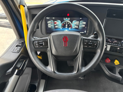 Kenworth T680 steering wheel and dashboard showing digital gauges and controls inside cab.