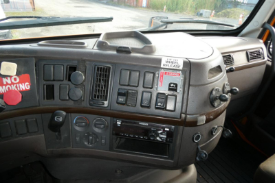 Dashboard of a Volvo truck interior showing steering column, instrument panel with various switches, vents, CD/Radio, and ignition area. Visible labels include NO SMOKING sticker on left and window/service tags.