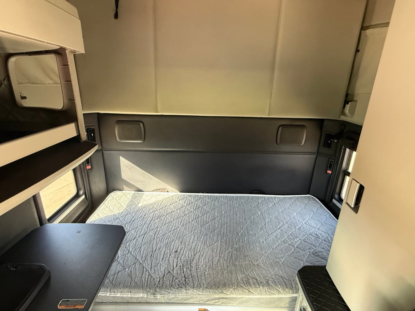 Kenworth T680 sleeper cab interior showing bed with mattress and side storage panels.