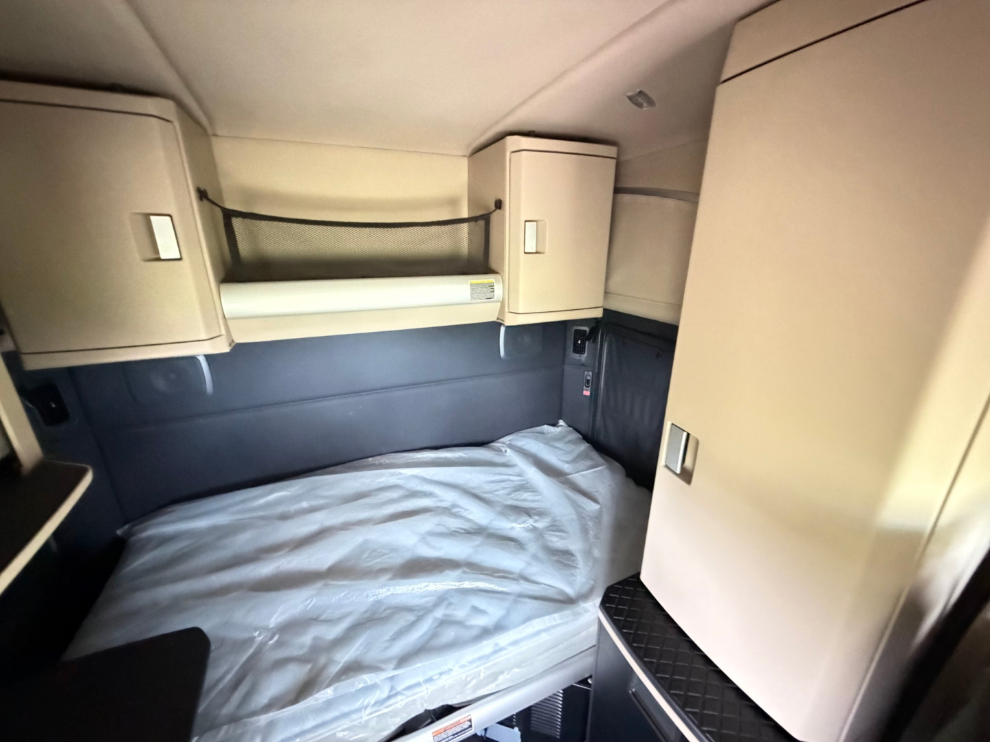 Kenworth T680 sleeper cab interior showing bunk bed area and overhead storage cabinets.