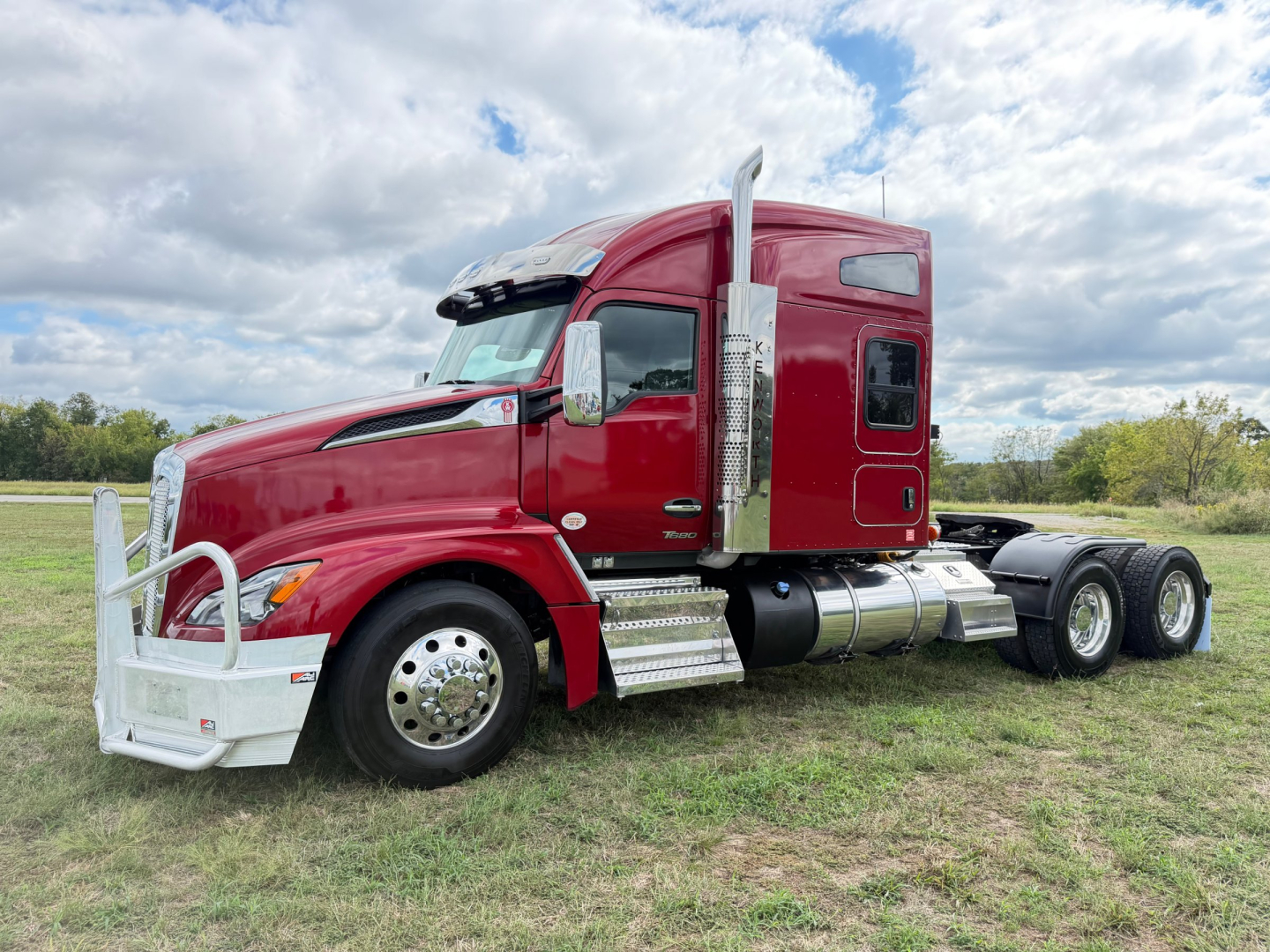 Kenworth T680 truck side view showing red semi with chrome exhaust stacks and dual rear axles.