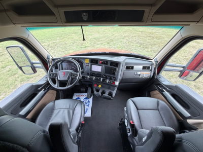 Kenworth T680 cab interior showing steering wheel, dashboard, and seats from front passenger perspective.