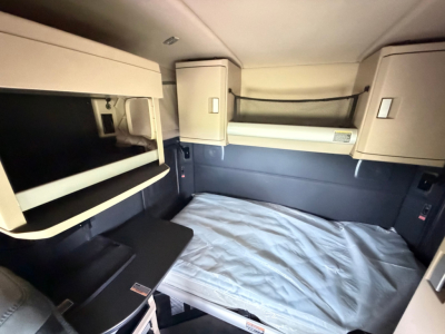 Kenworth T680 sleeper cab interior showing bunk bed area and storage cabinets.