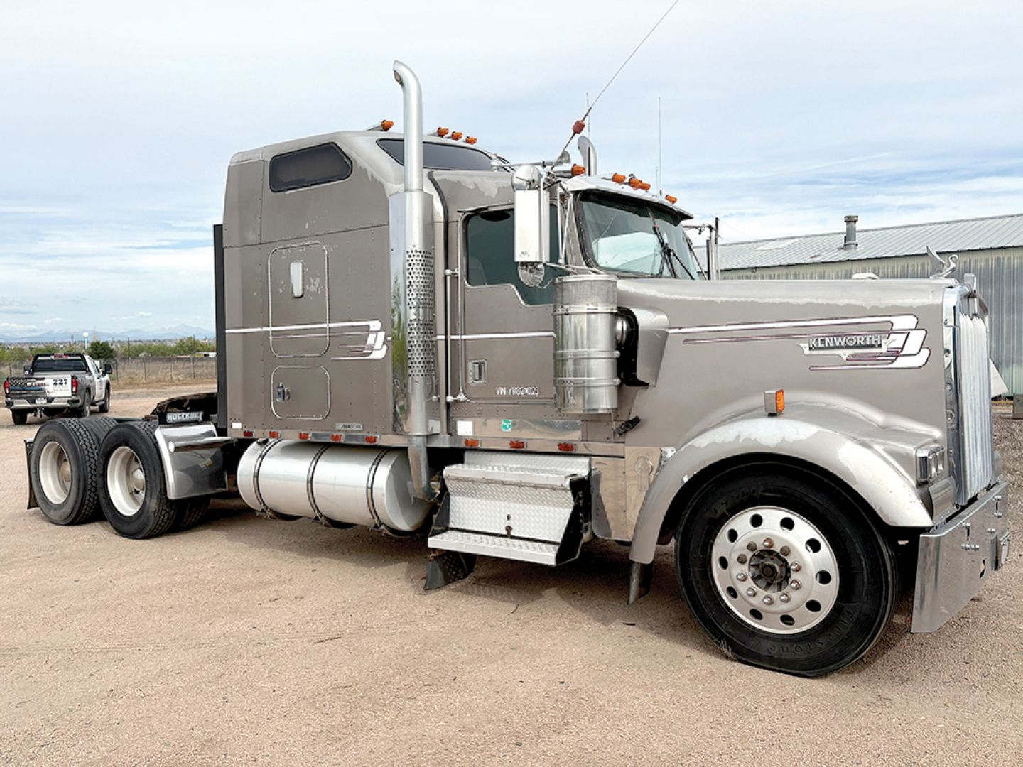 Kenworth W-900L AeroCab conventional sleeper truck side view showing chrome fuel tanks, air filters, and large exhaust stack with raised grille and hood ornament.