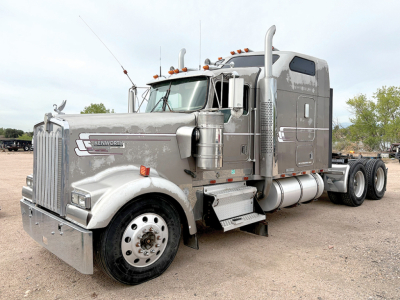 Kenworth W900L AeroCab tractor in side-angle view showing chrome exhaust stacks, fuel tanks, and dual rear axles.