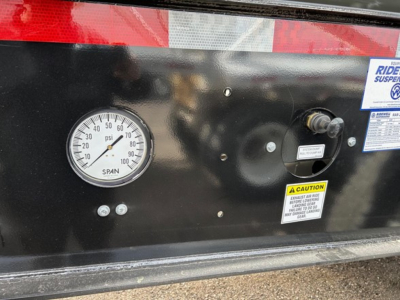 Dial gauge mounted on black metal panel showing pressure in psi, with label SPAN and surrounding warning sticker and small bolts.