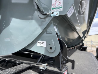 Trailer hitch area of Smithco air ride side dump showing mounting bracket and warning labels with tag 7904