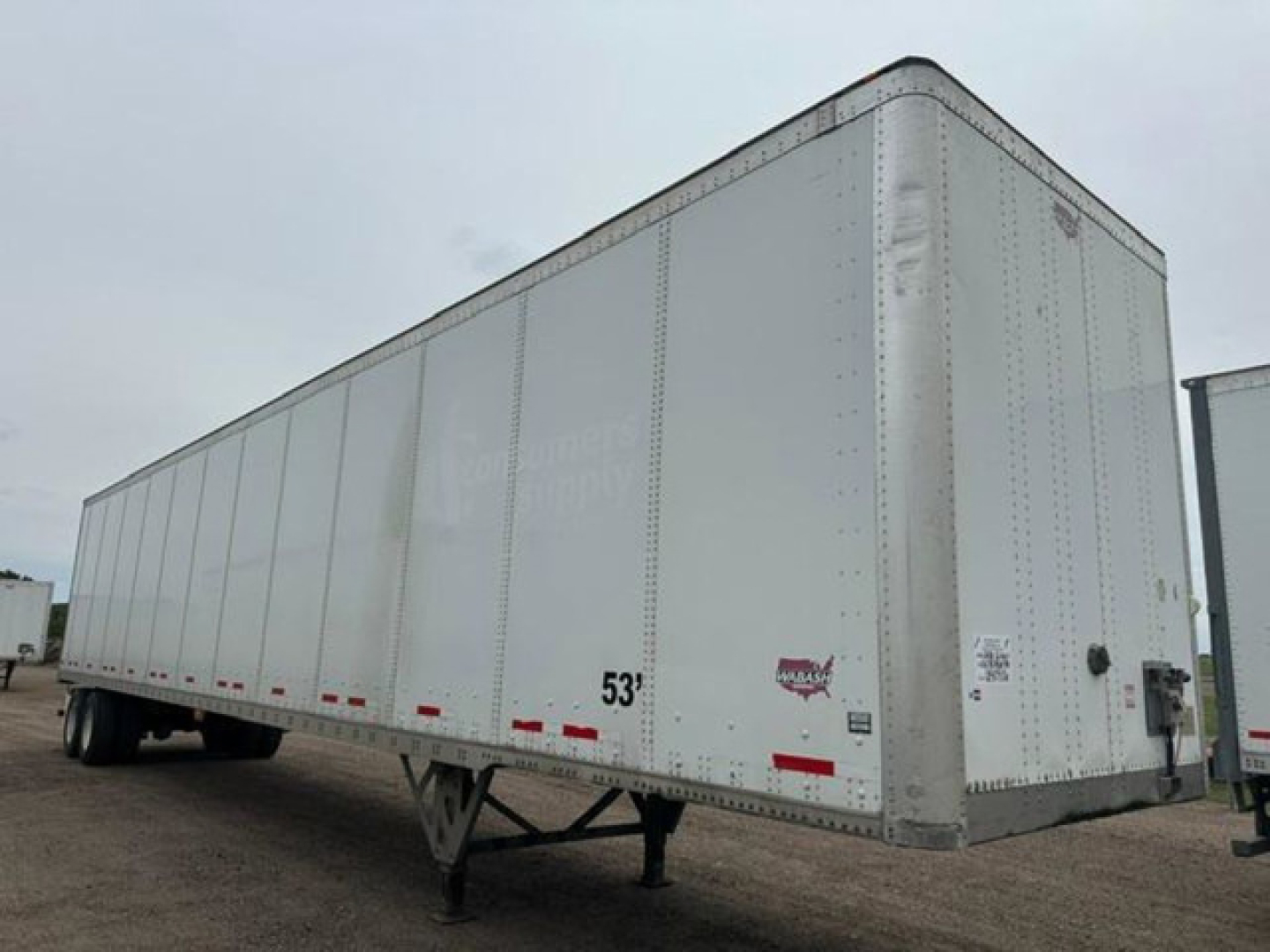 Trailer side view showing a 53 ft white Wabash van trailer with stock numbers and VIN plate visible.