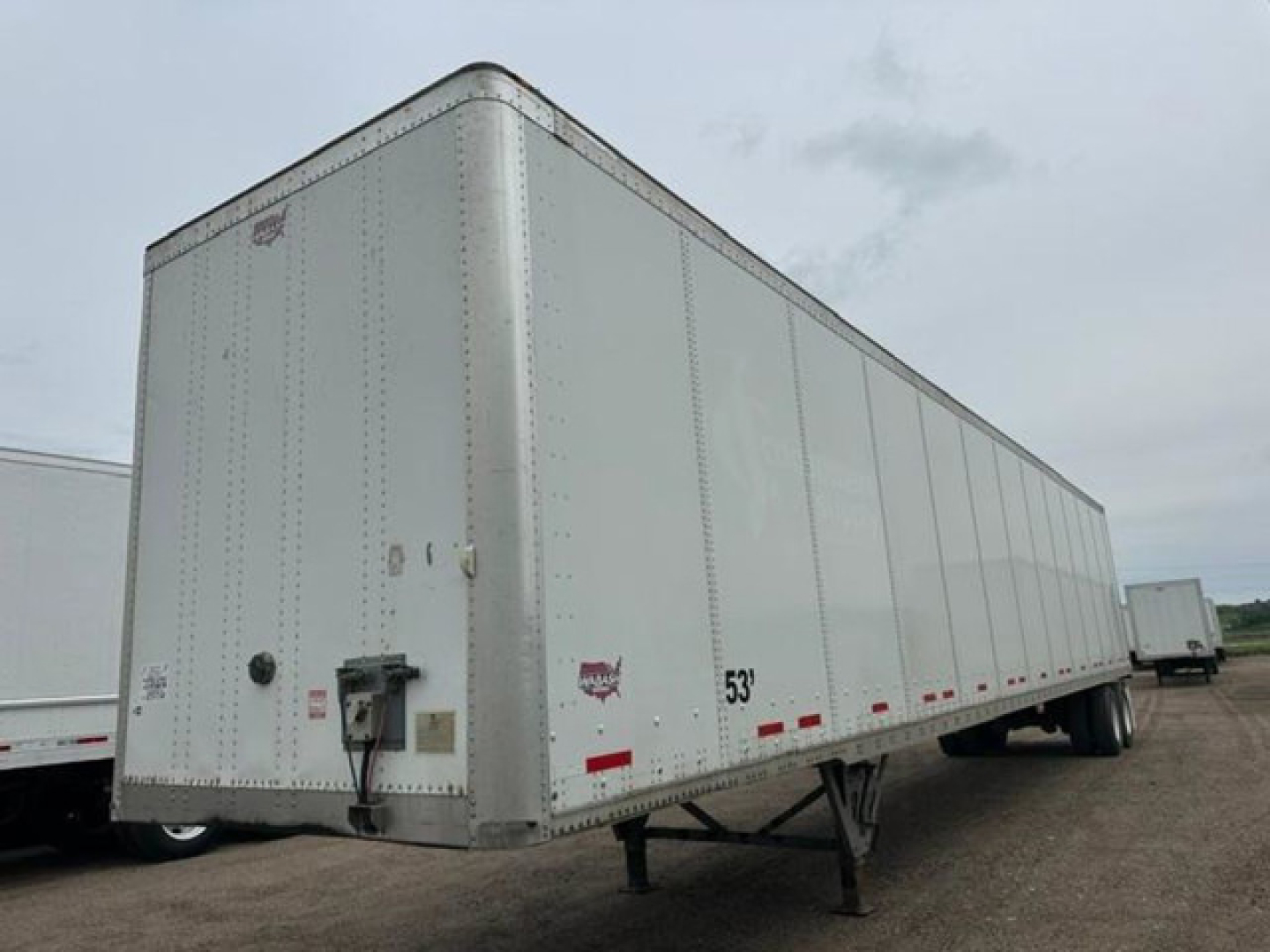 Trailer side view showing a white 53' Wabash van trailer with rear landing gear and reflective tape along the bottom edge.