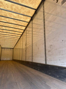 Trailer interior showing wooden floor and white insulated side walls with metal rails, empty cargo area in a 2016 Wabash van trailer.
