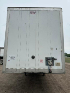 Rear view of a 2016 Wabash van trailer with riveted aluminum panels, rear doors, and a service receptacle/connector at the lower right.