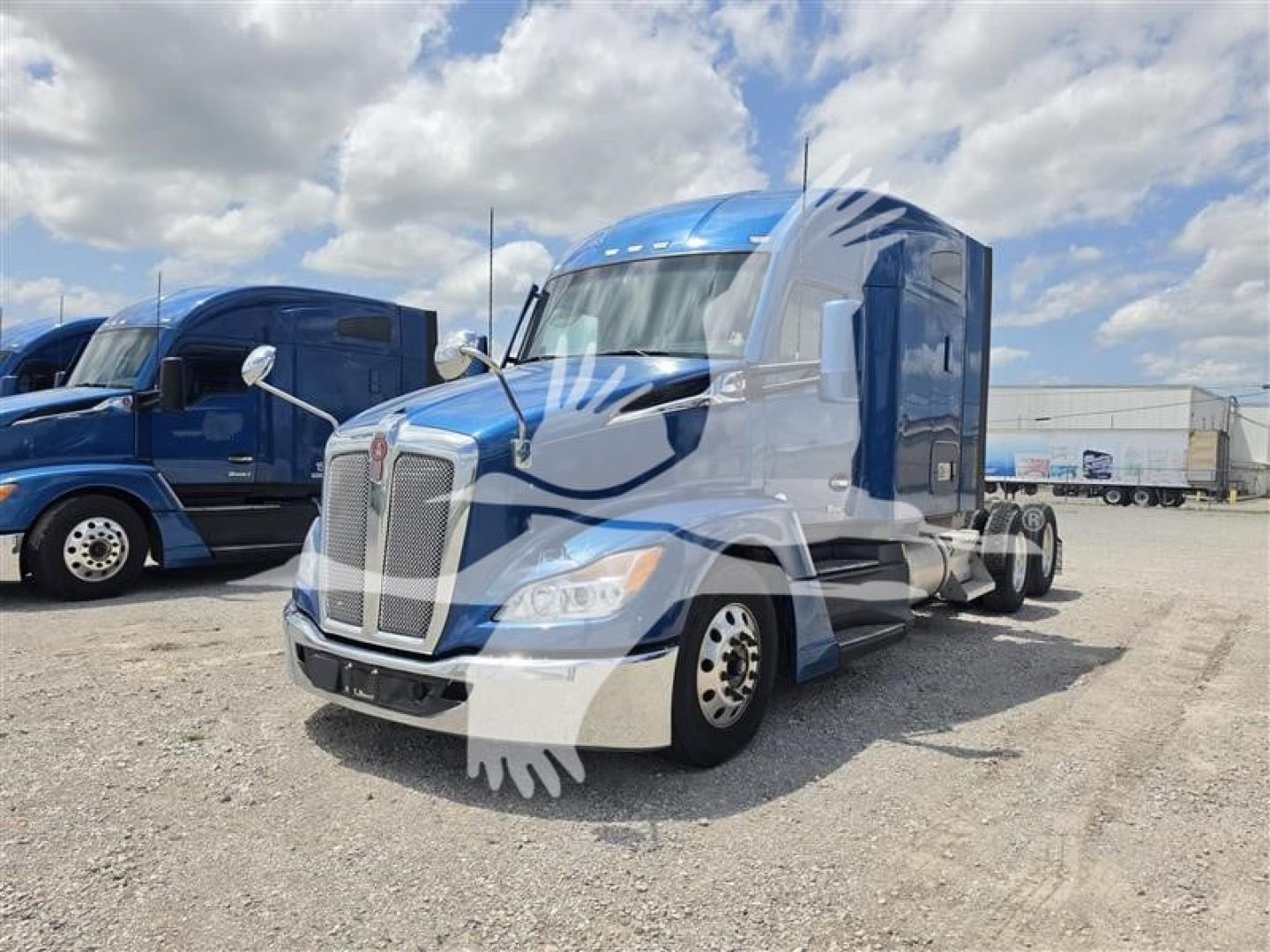 Kenworth T680 conventional sleeper tractor in blue and white with chrome grille, showing front and side view in a truck lot.