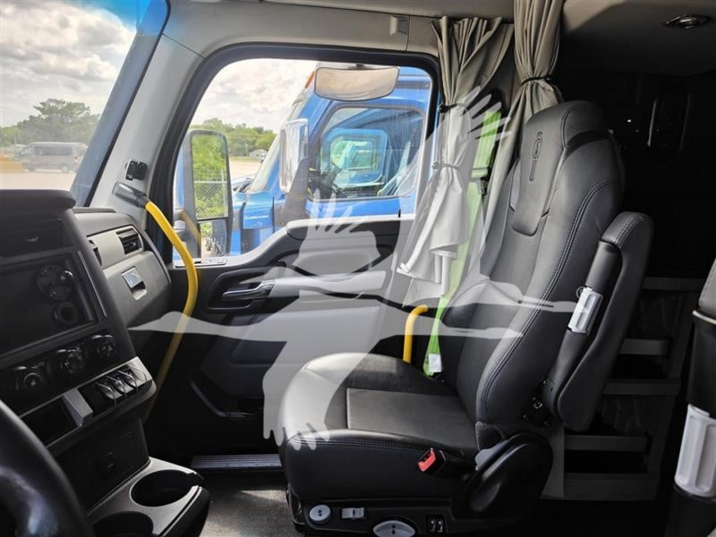 Truck interior showing driver's seat and dashboard area of a Kenworth T680 sleeper cab; steering wheel, control panels, and window with exterior truck visible.