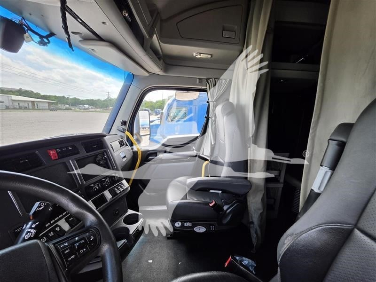 Kenworth T680 truck interior cab view showing dash, steering wheel, and bunk area with plastic covers and mirror glare.