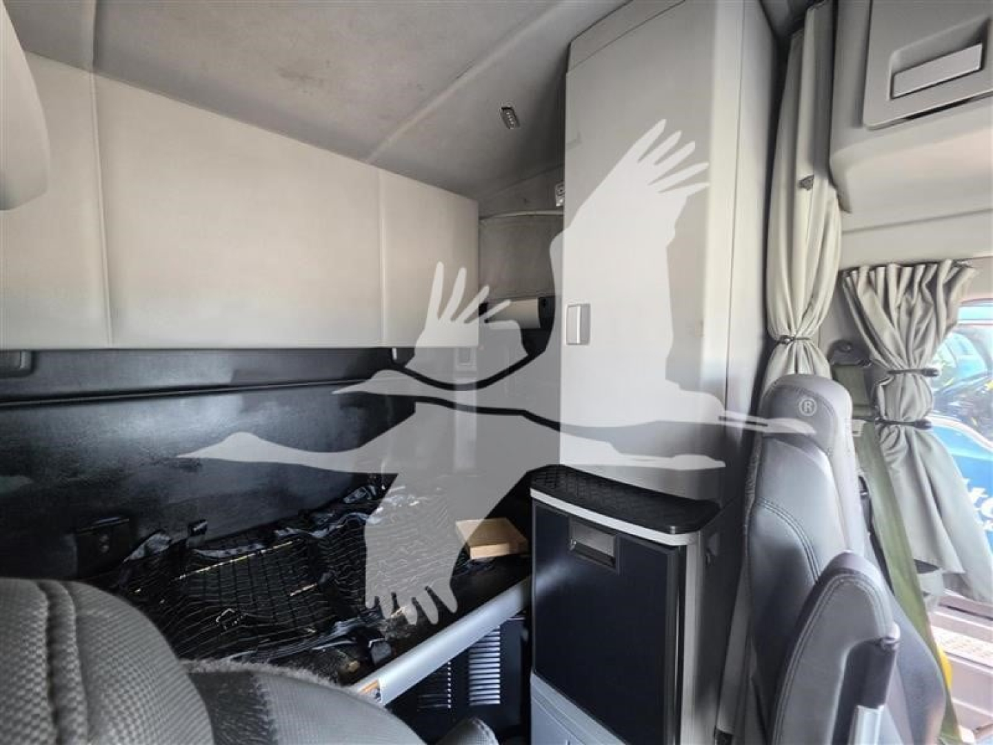 Cab interior of a 2023 Kenworth T680 showing sleeper area with storage cabinets and curved partition.