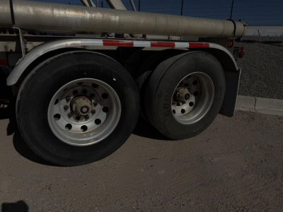 Truck trailer wheel area showing dual rear axles, metallic wheels, and underside of a 2018 Heil pneumatic dry bulk tank.