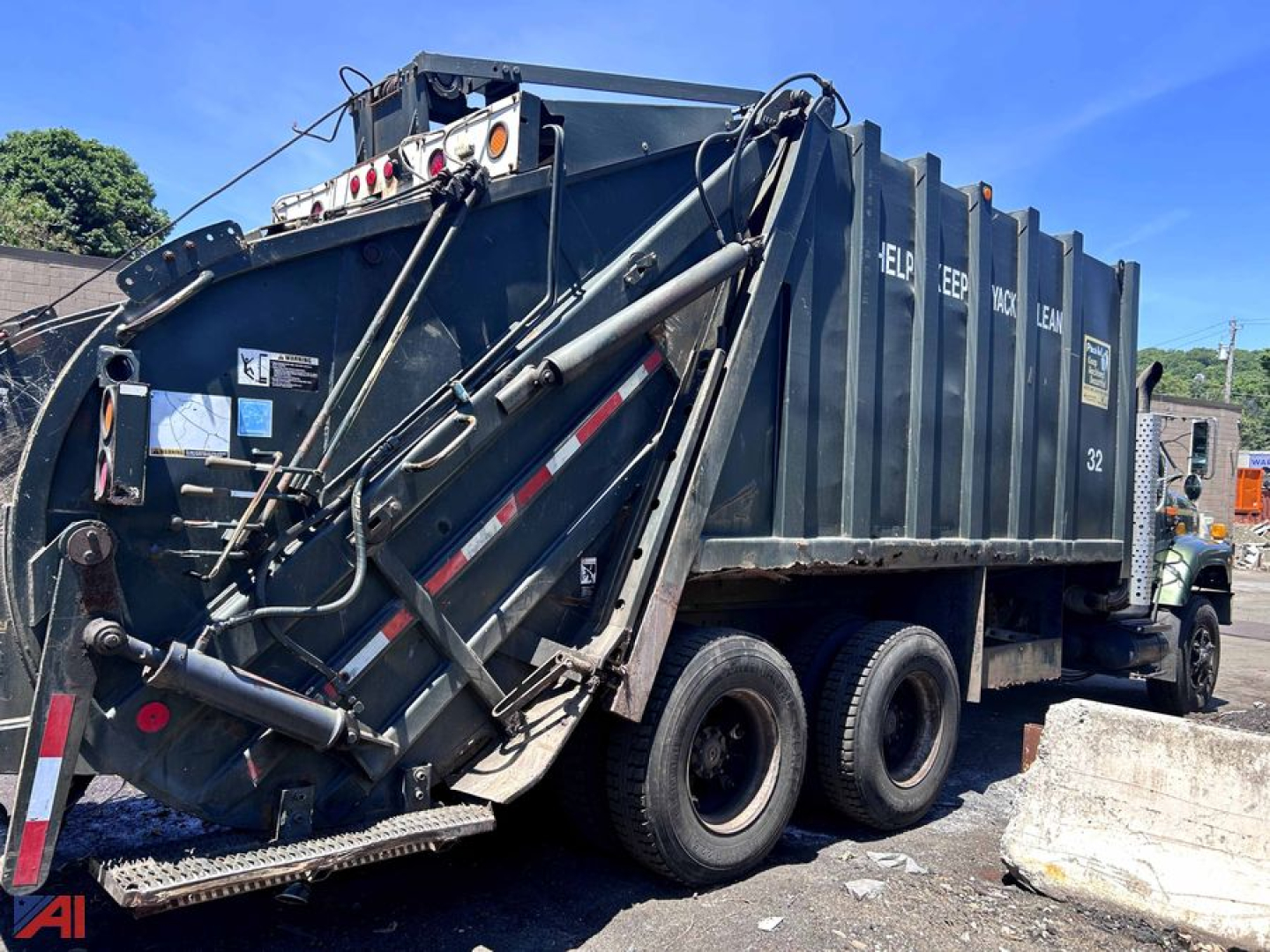 Dump truck rear and side view showing a large blue dump body with hydraulic mechanism and dual rear axles on a International 2654 Packer.