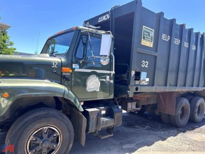Dump truck from the cab side showing International 2654 with green paint, number 32 on door, and a large black dumpside container.