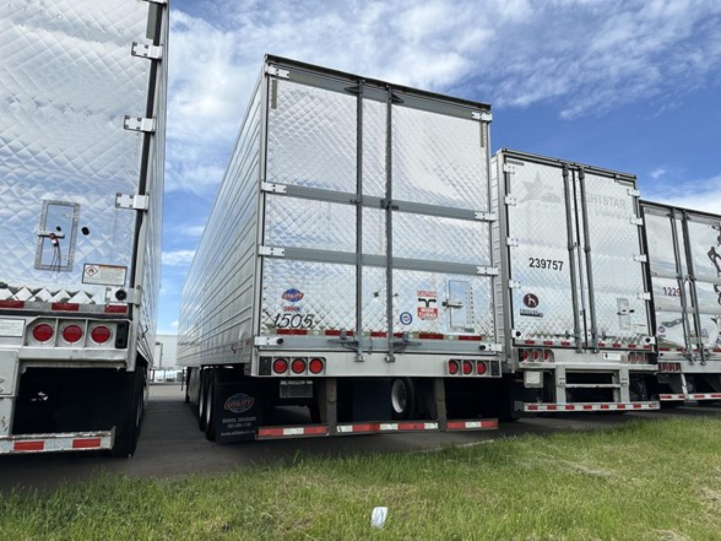 Rear view of a 2020 Utility 3000R trailer among several similar trailers; visible are reflective aluminum walls, rear doors, taillights, bumper, and mudflaps.