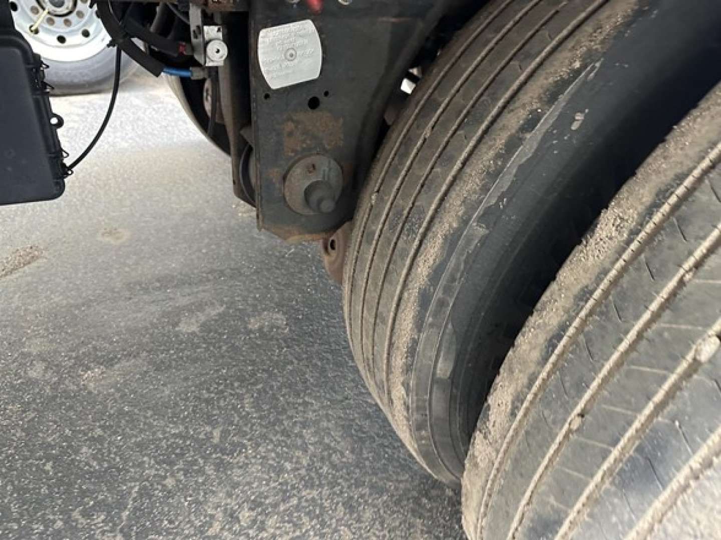 Trailer wheel area of a 2020 Utility 3000R with dual rear axles, showing the dual tires, suspension hanger, and a rust-colored mounting bracket.
