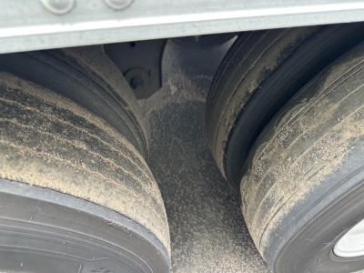 Trailer dual tires showing dirty wheel hubs and mud on the tires; part of the reefer trailer body visible above.