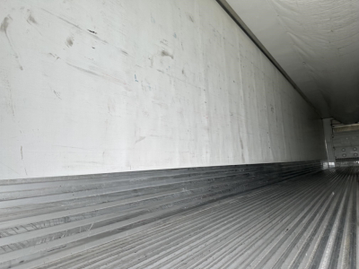 Trailer interior with ribbed metal floor and smooth side wall; empty cargo area with light from rear door.