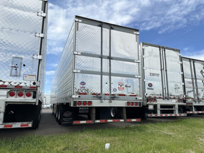 Rear view of a 2020 Utility 3000R trailer among several similar trailers; visible are reflective aluminum walls, rear doors, taillights, bumper, and mudflaps.