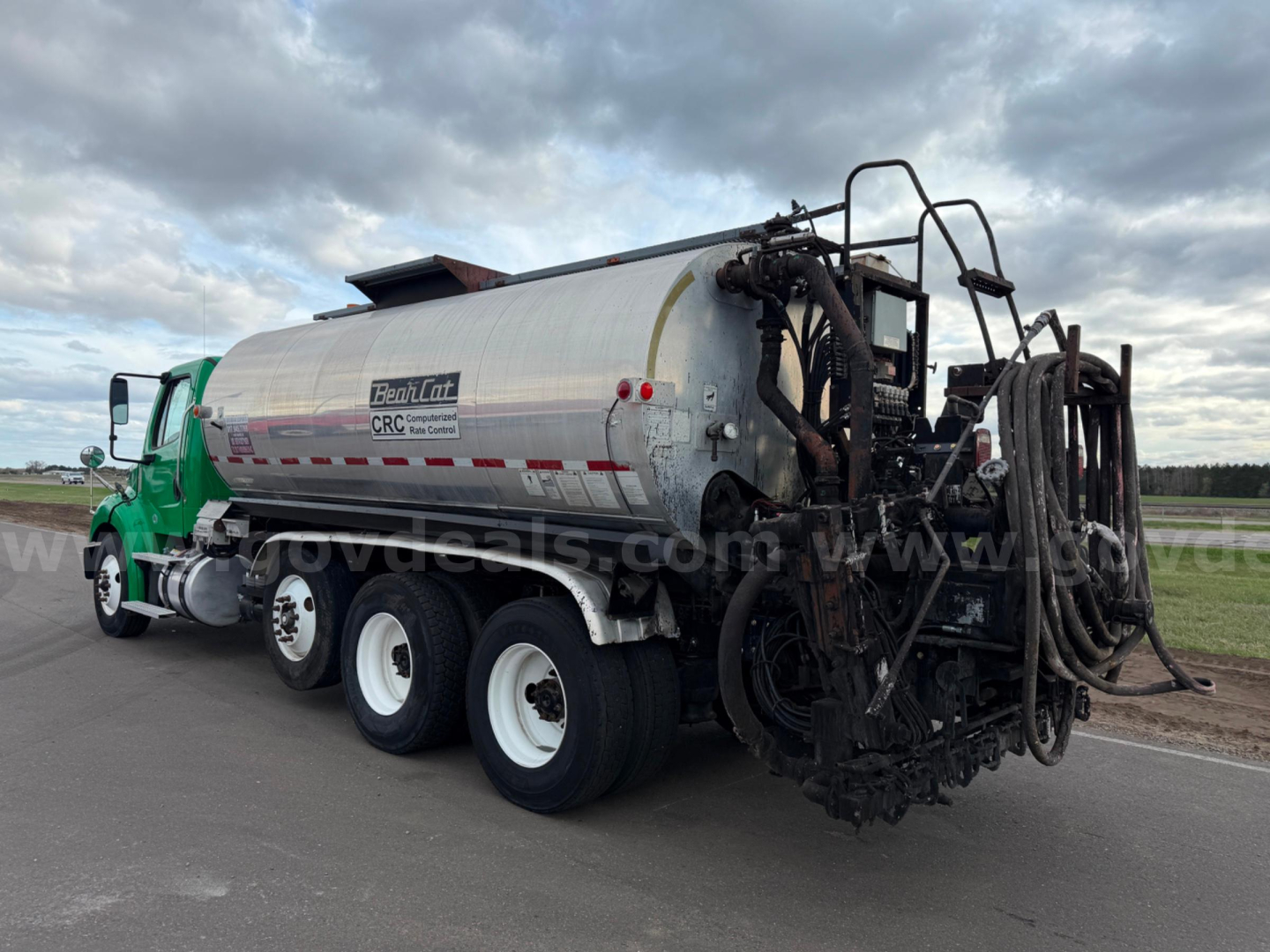 Freightliner BearCat asphalt hot oil tanker truck with green cab and silver tank, rear hose reel equipment, side view
