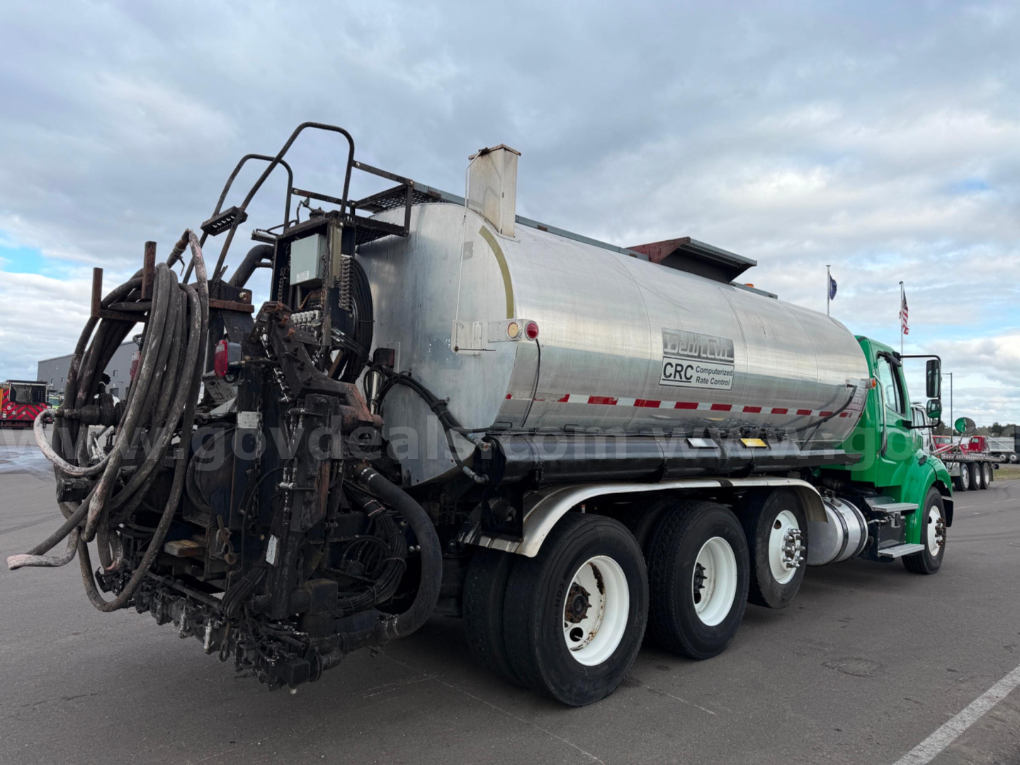 Freightliner Bearcat tanker truck showing tank and rear hose reel assembly with green cab and multiple axles.