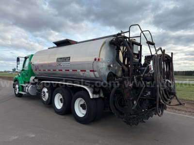 Freightliner BearCat asphalt hot oil tanker truck with green cab and silver tank, rear hose reel equipment, side view