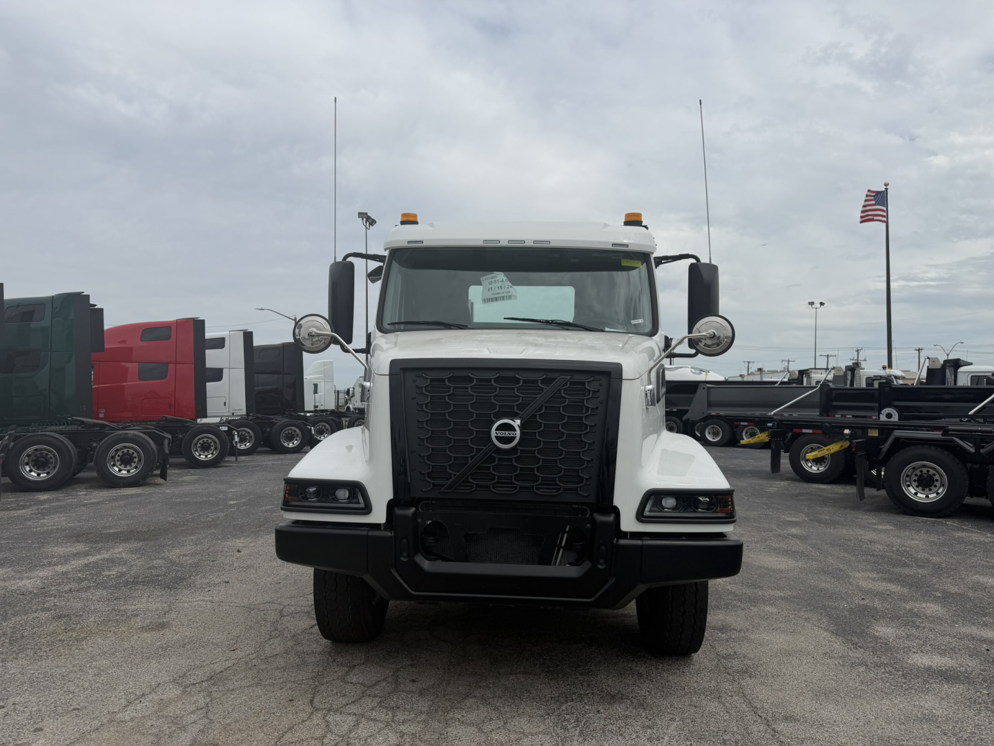 Volvo VHD86B300 cab and chassis truck front view showing large black grille, Volvo emblem, dual round mirrors, yellow clearance lights, and white cab.