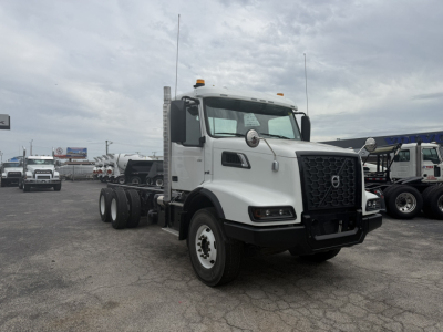 Volvo VHD86B300 cab and chassis truck in a dealership lot showing front view with grille and cab, white exterior.