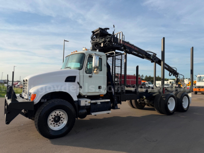 2007 Mack CV713 grapple truck side view showing crane arm and carrier, white cab, black underbody, visible front wheel, ladder steps, and hydraulic components.