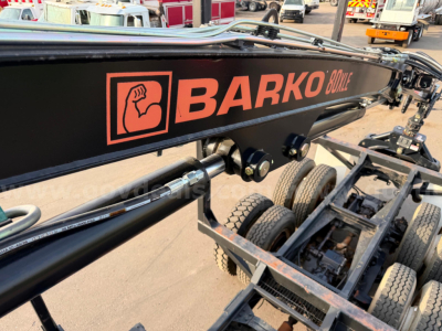 Grapple truck component with 'BARKO' logo on black boom arm, showing hydraulic joints and crane chassis wheels.