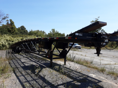2017 Kaufman 3-car hauler trailer side view showing elevated deck, gooseneck hitch, and support legs in an outdoor lot.