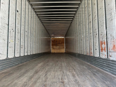 Interior of a 2015 utility van trailer showing empty cargo area with metal walls and wooden rear door.
