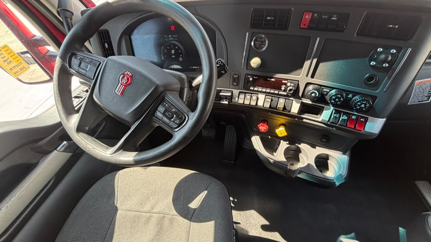 Kenworth T680 semi-truck interior dashboard and steering wheel with controls and gauges visible.