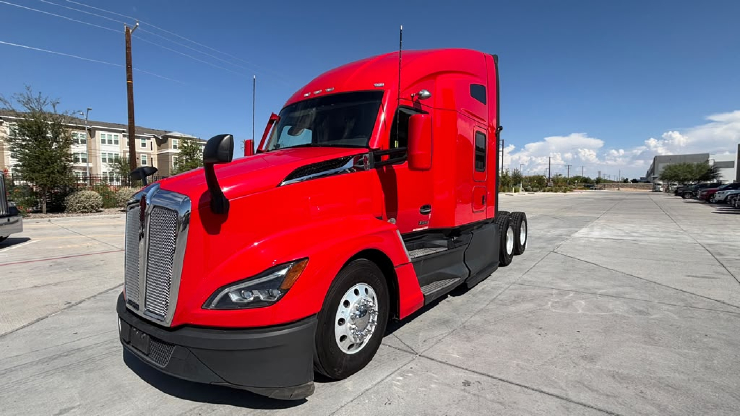 Kenworth T680 semi truck in red, front-left view. Showcases cab and mounted mirrors, hood, headlights, and front grille.