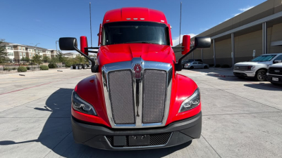 Front view of a red 2023 Kenworth T680 truck showing grille, headlights, and bumper.