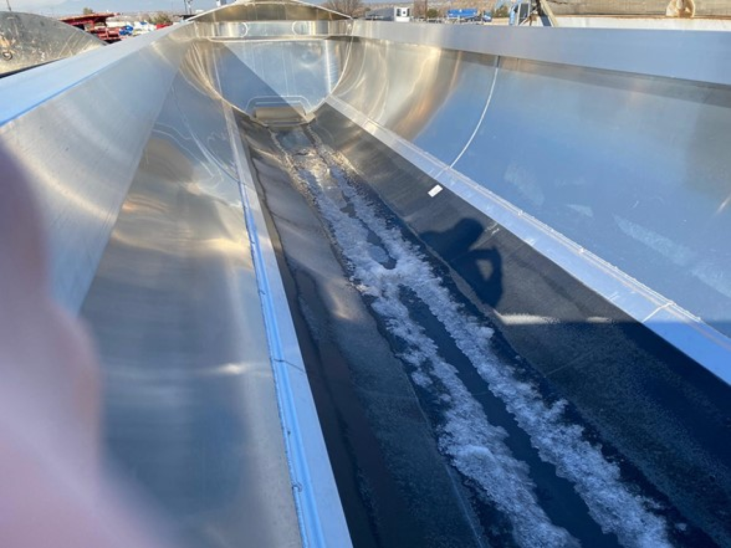 Dump trailer interior showing metal end dump trough with snow and ice along the channel