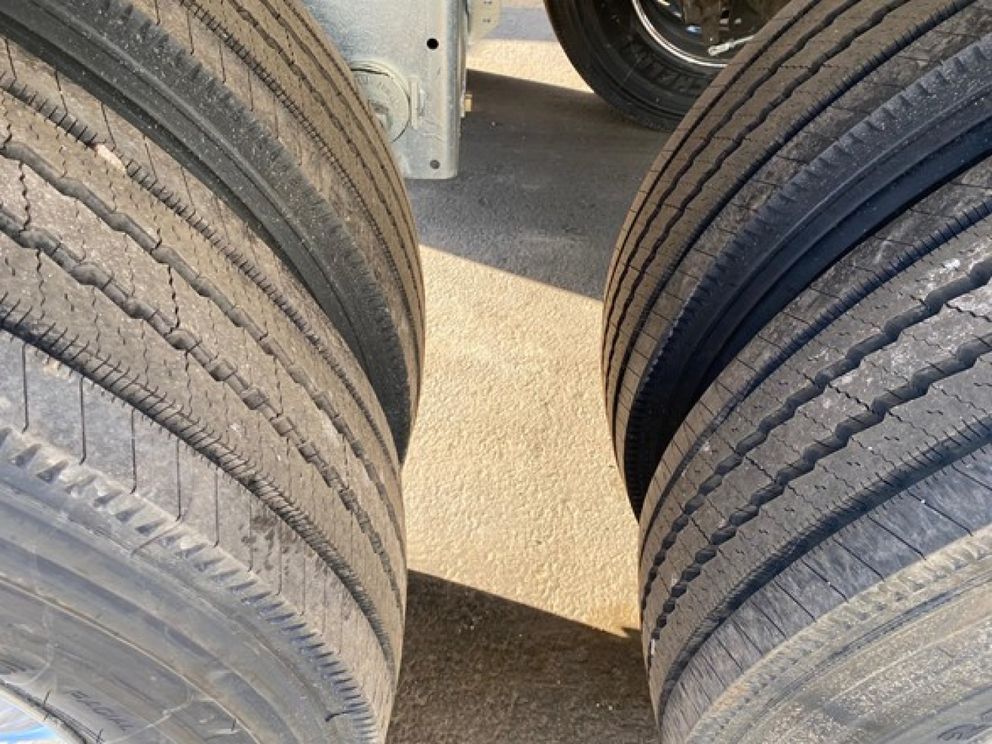 Dual rear truck tires with tread patterns visible; part of a trailer chassis and wheel well in background.